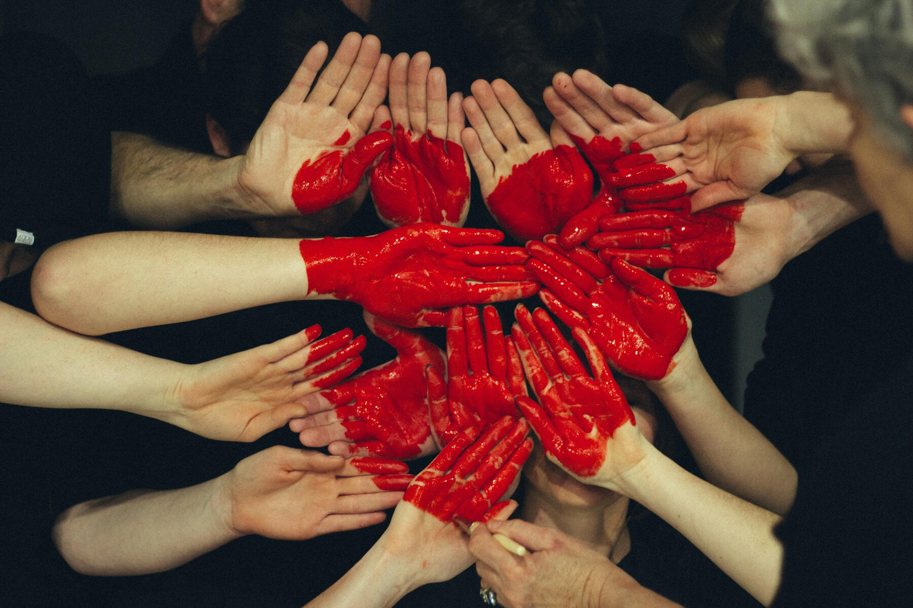 Groupe de personnes unissant leur main comme support pour y peindre un coeur rouge
